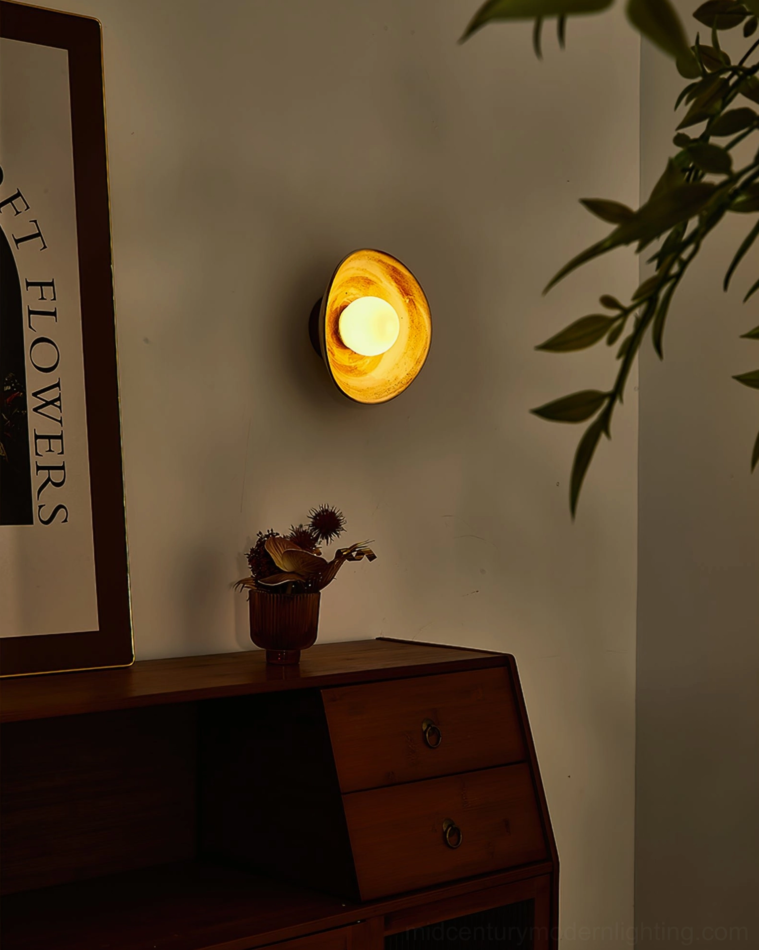 Eala wall lamp glowing against corner with framed artwork, demonstrating ambient light diffusion