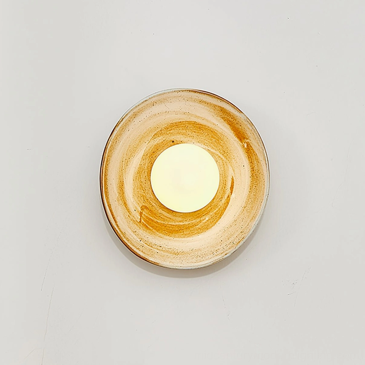 Eala wall lamp with smooth brown ceramic glaze and warm glowing frosted bulb on white background
