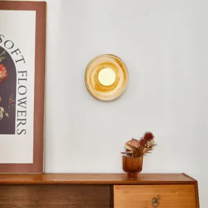 Eala wall lamp illuminated on console table with warm ambient glow, styled with dried flowers and botanical decor