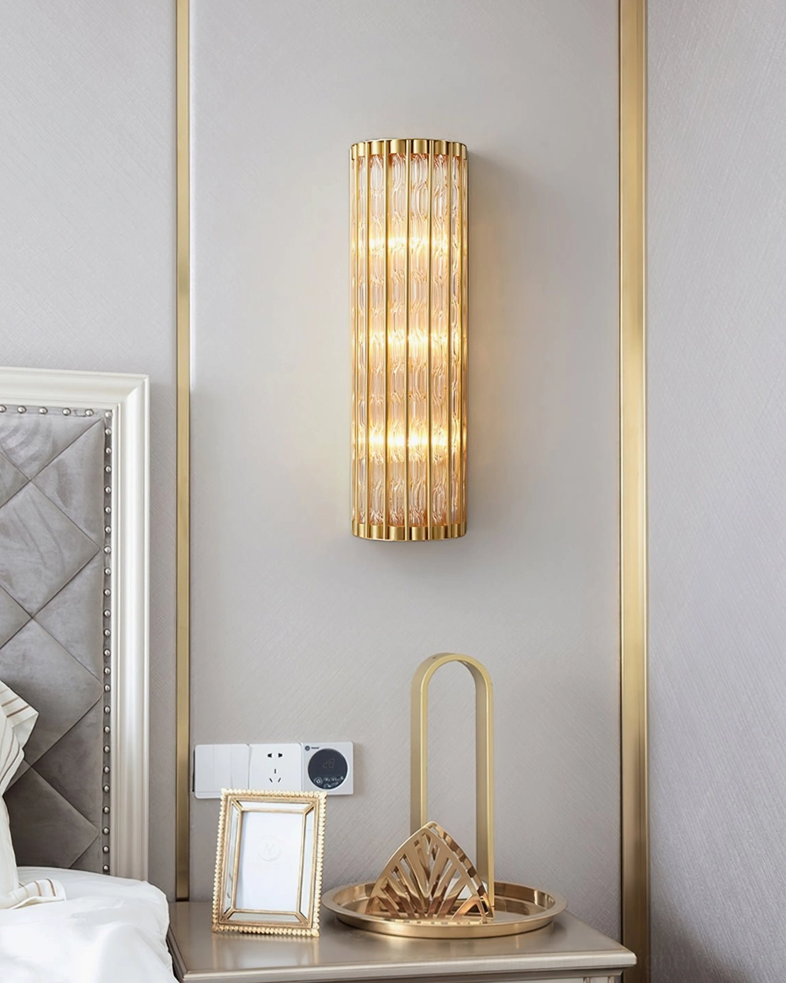 Luxury bedroom wall sconce with brass finish beside bedside table, soft ambient lighting in modern master bedroom