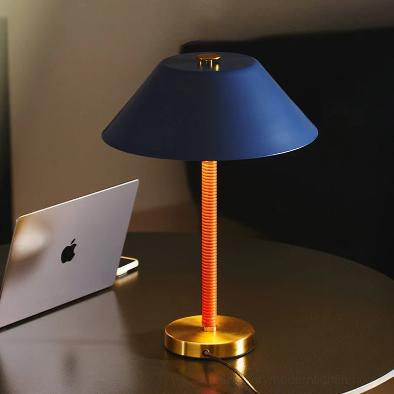 Eave mid-century modern table lamp on round dark dining table, navy blue metal shade with brass base and orange ribbed stem