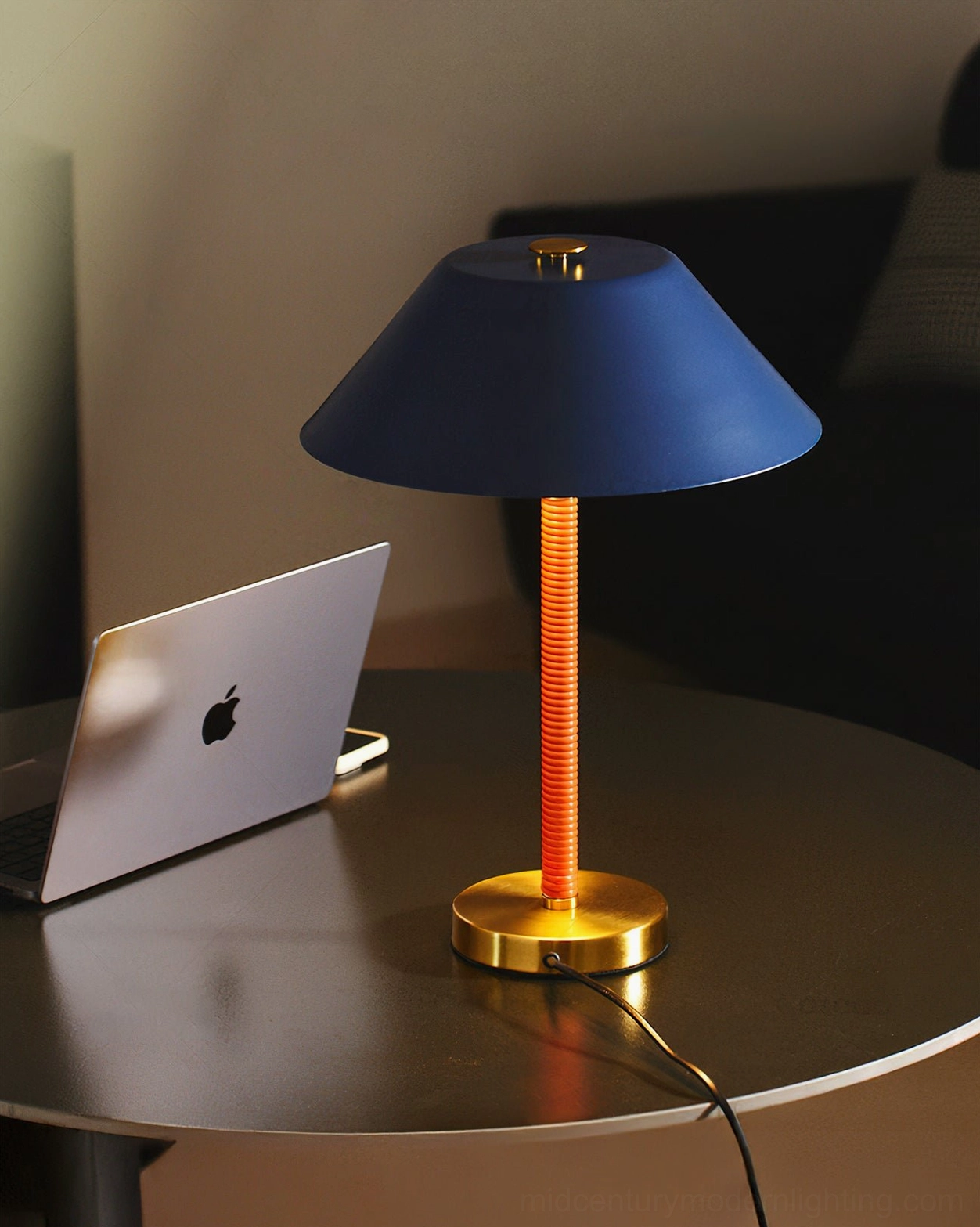 Eave mid-century modern table lamp on round dining table with workspace, three-quarter view showing brass base and stem
