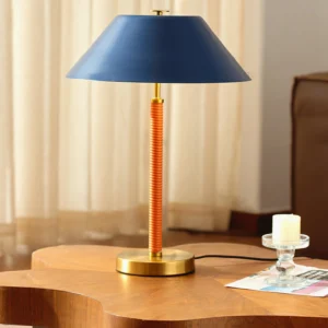 Eave mid-century table lamp on wooden side table in modern living room with candle decor, navy shade and brass base