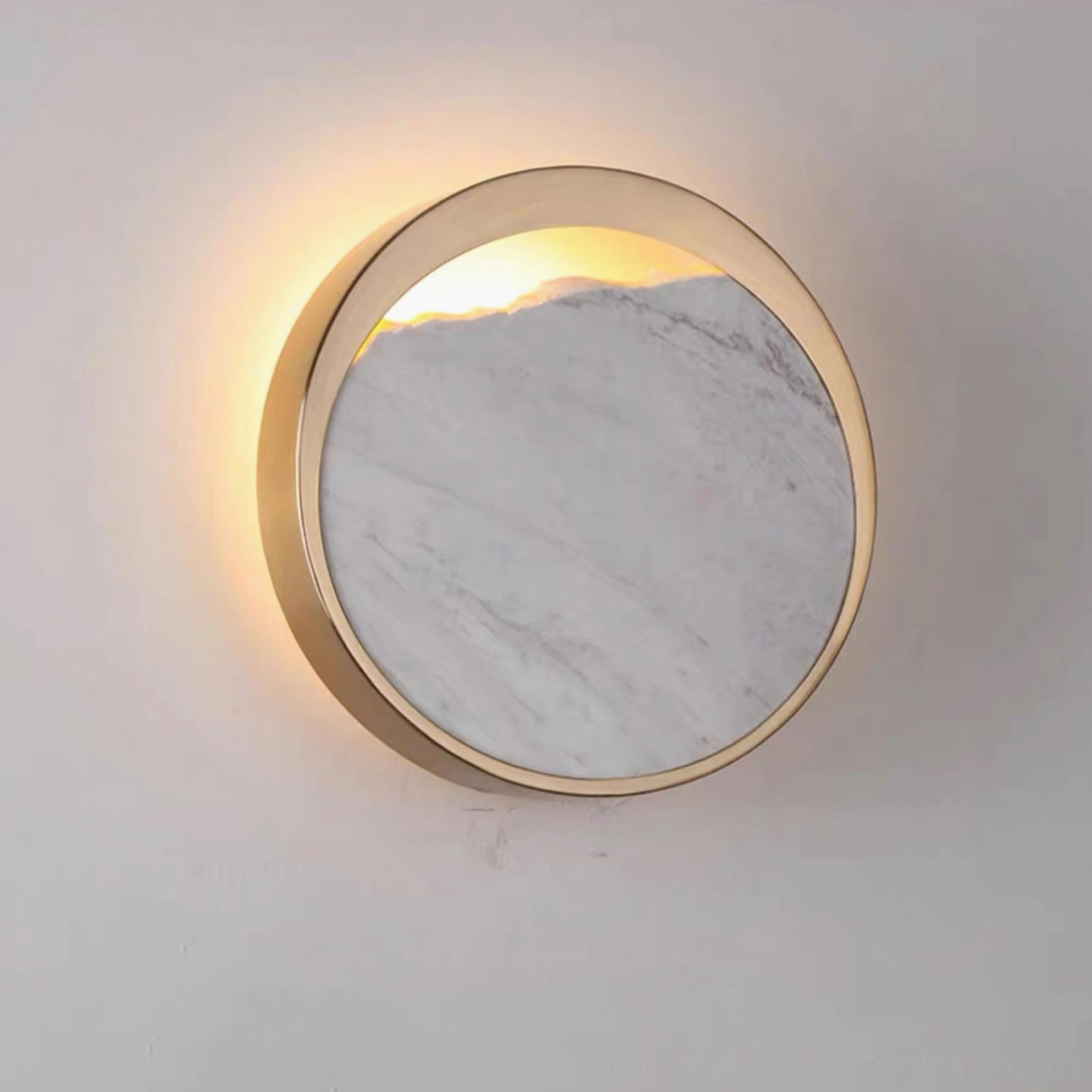 Backlit Eclipse marble wall lamp glowing with warm light against grey studio background