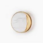 Eclipse marble wall lamp front view with gold metal frame and white hand-carved stone shade against studio background