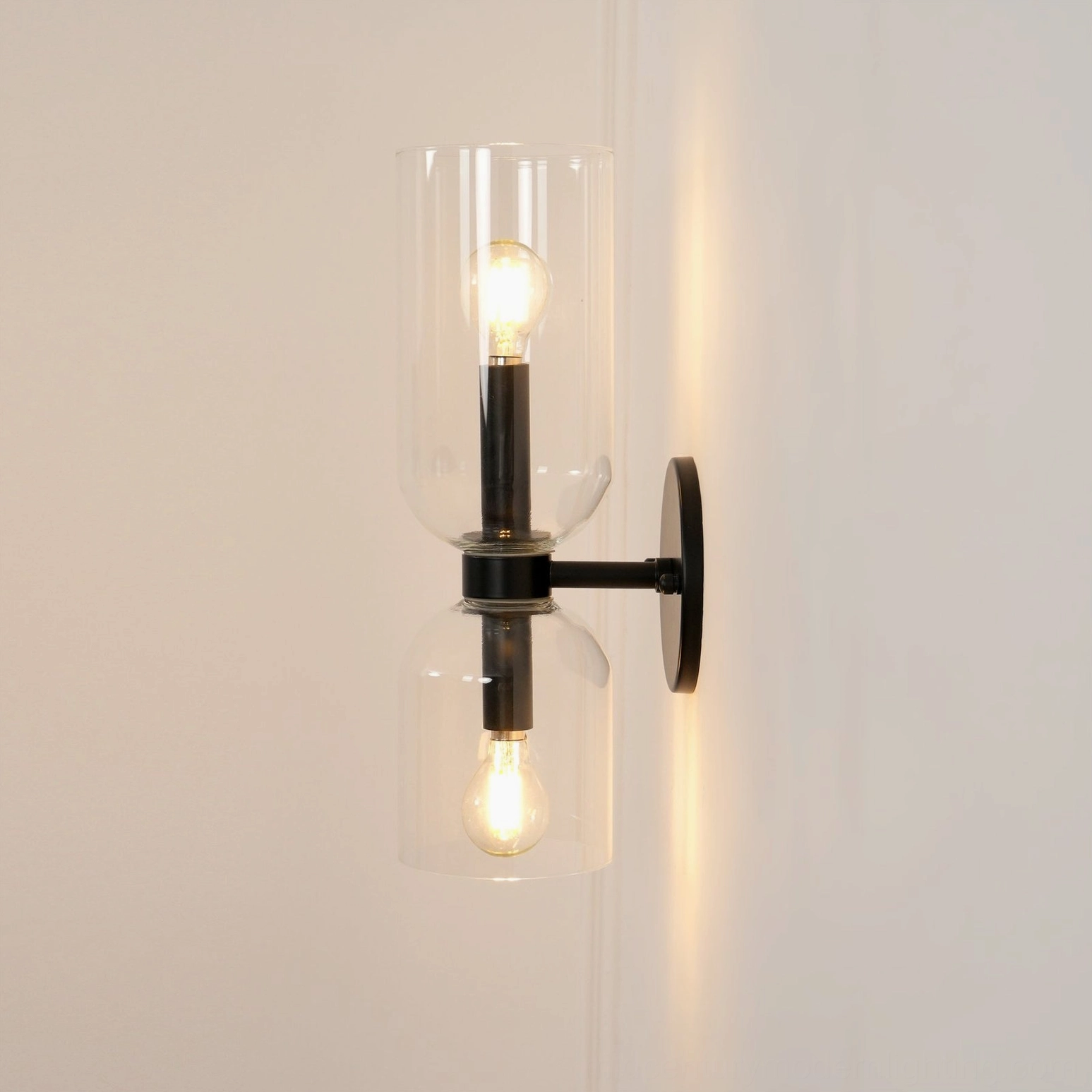 Contemporary glass wall lamp featuring transparent shade with metal frame architectural detail