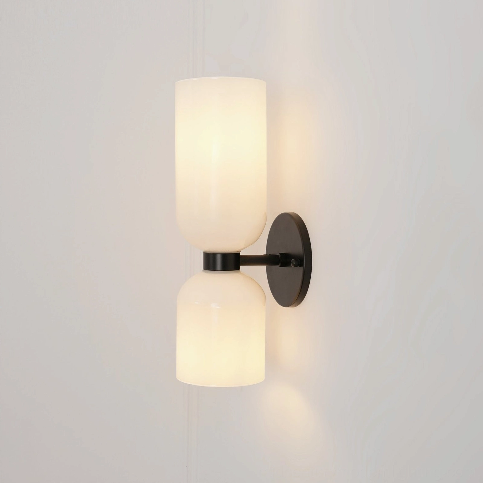 Modern designer sconce with frosted glass shade creating ambient glow and refined metal base