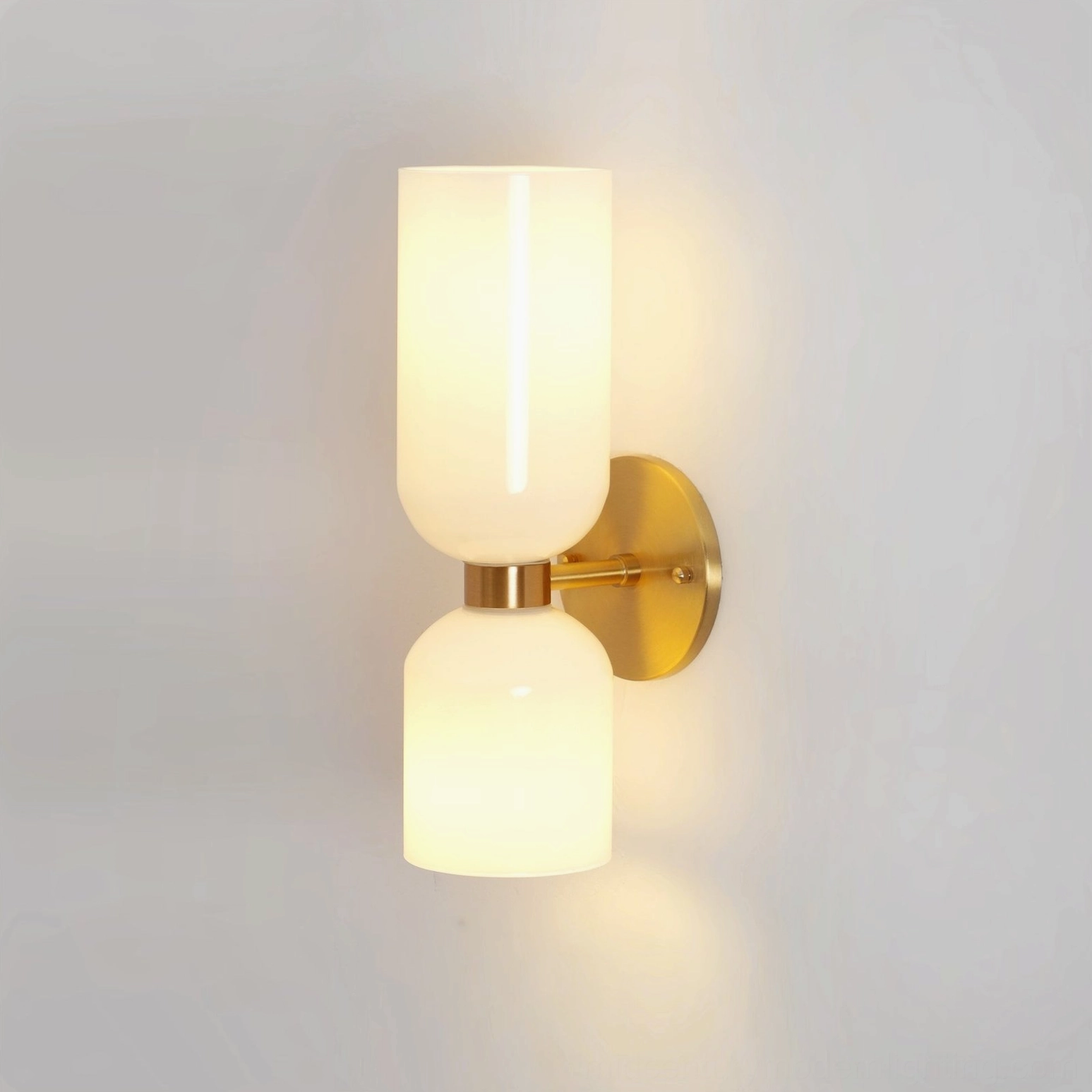 Hand-blown glass wall sconce with off-white frosted shade and polished gold metal frame on studio background