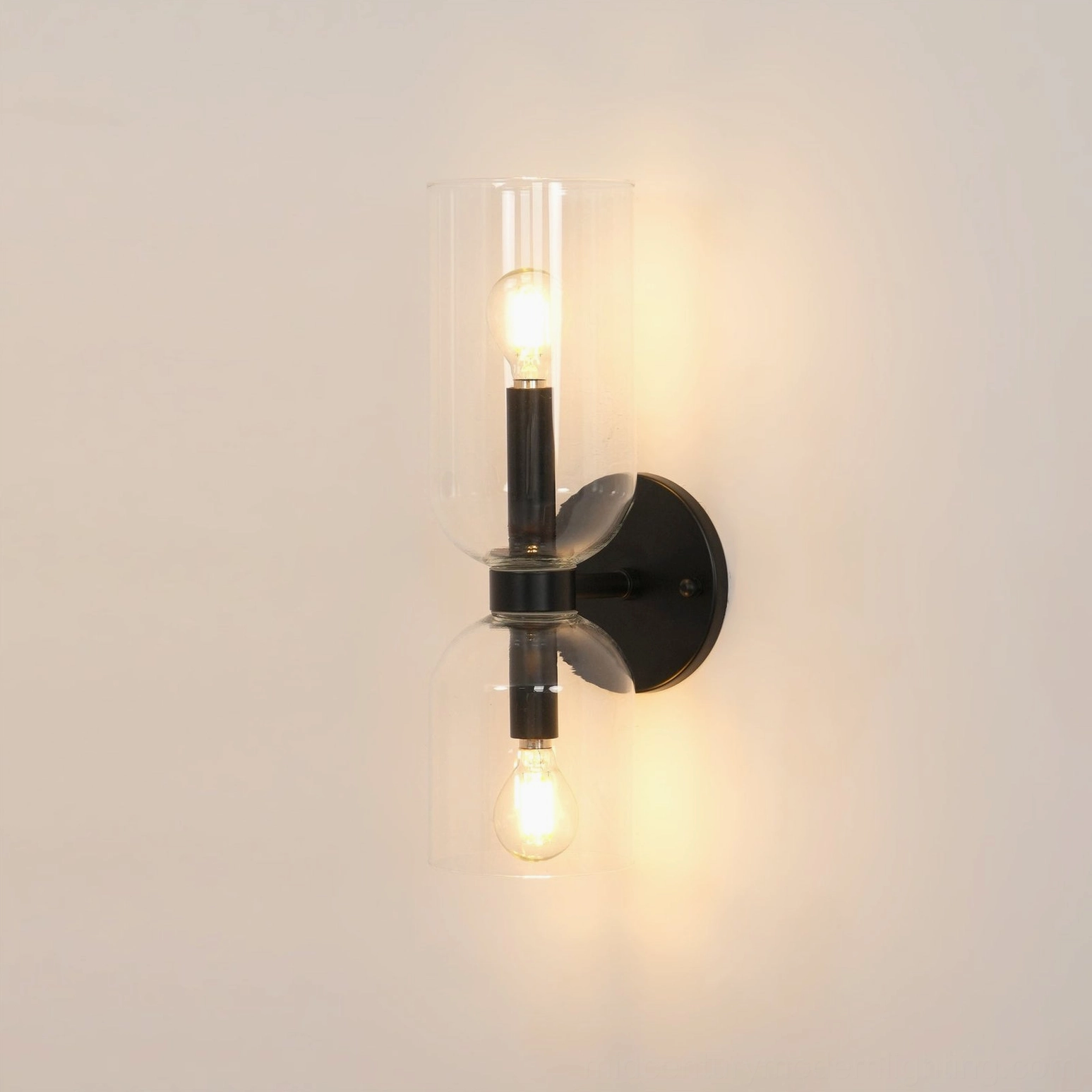 Modern wall sconce with clear glass shade and warm brass finish mounted on studio background