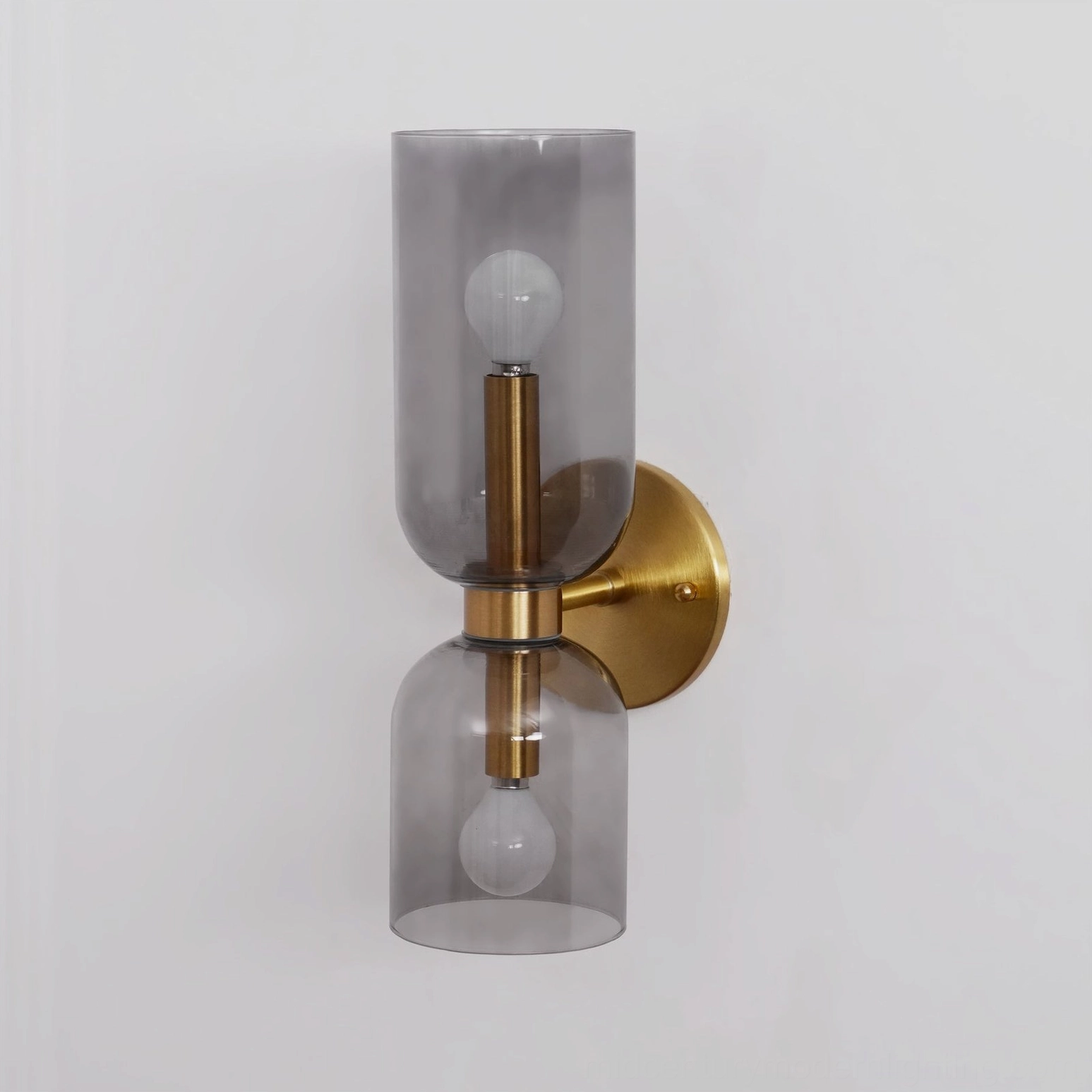 Architectural glass wall sconce with smoked grey blown glass shade and brass hardware, unlit studio shot