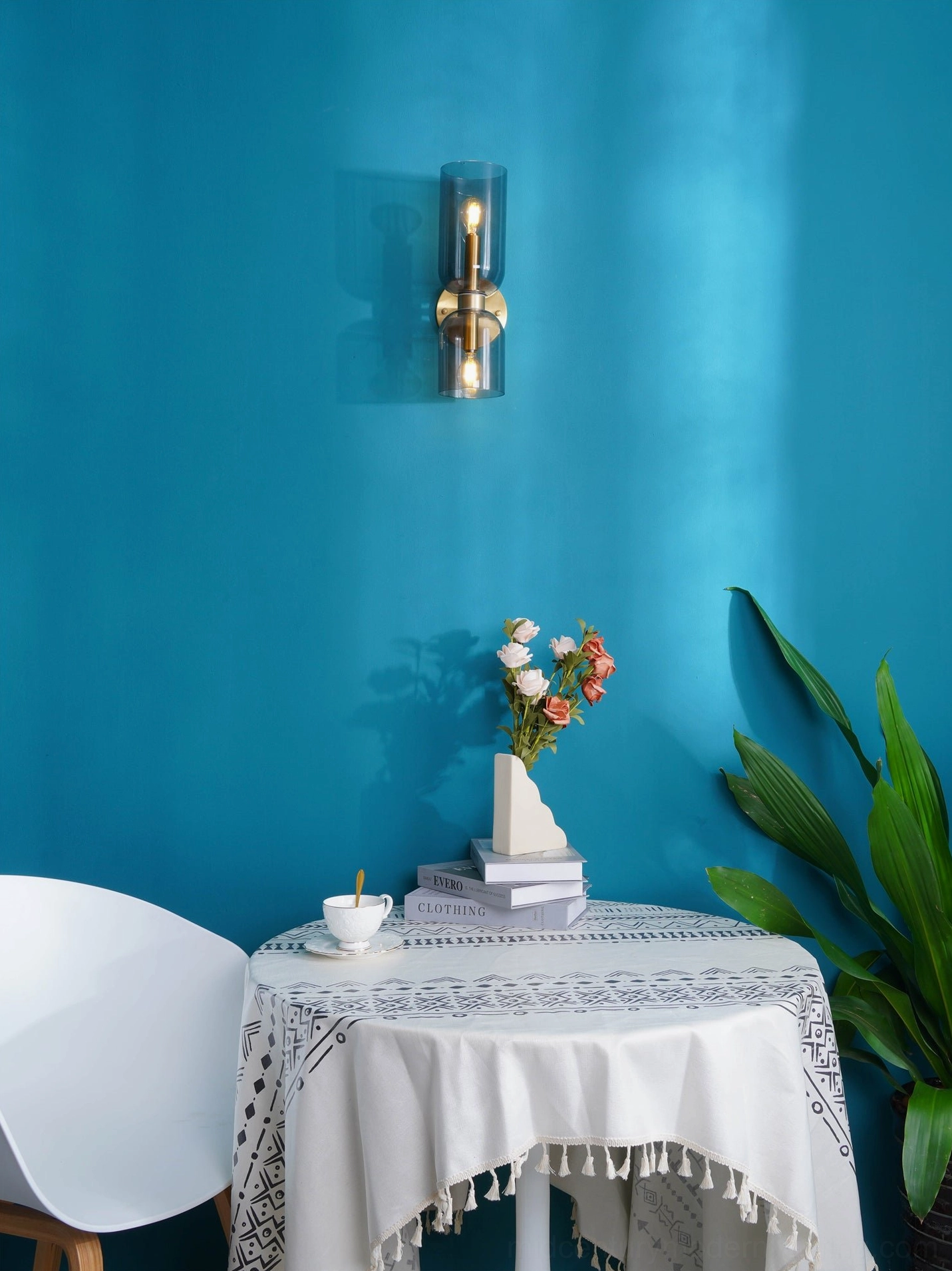 Hand-blown glass sconce mounted in minimalist dining area with polished metal finish and warm glow