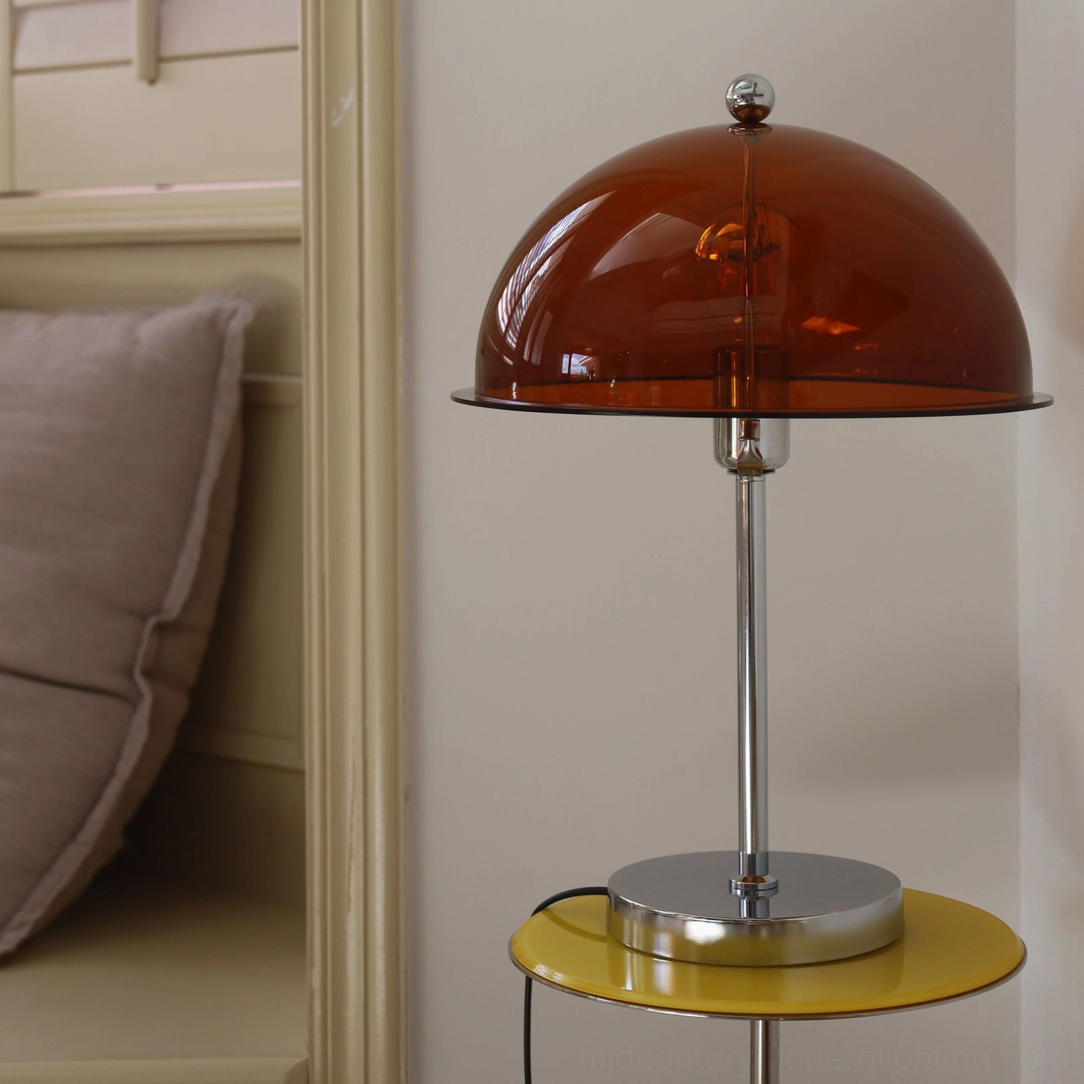 Edinburgh table lamp with dark amber acrylic shade beside bedroom nightstand, side angle perspective