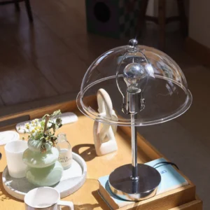 Edinburgh table lamp with clear shade on side table showing angled perspective and polished chrome hardware detail