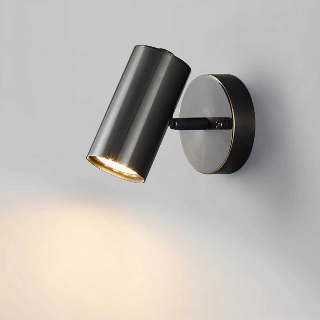 Eduard brass wall sconce with articulating cylinder shade casting warm directional light