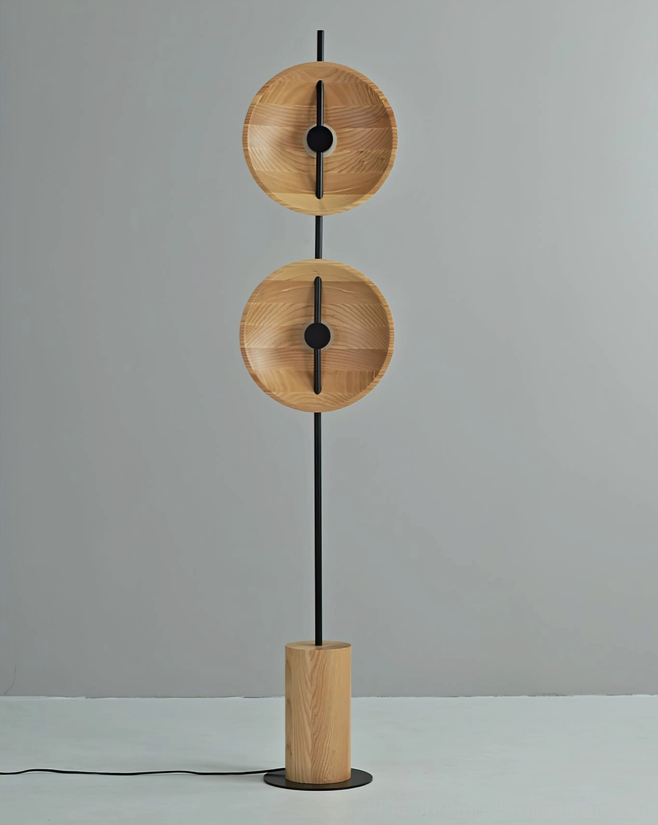 Eine wooden disc floor lamp unlit showing cylindrical wood base and natural material finish