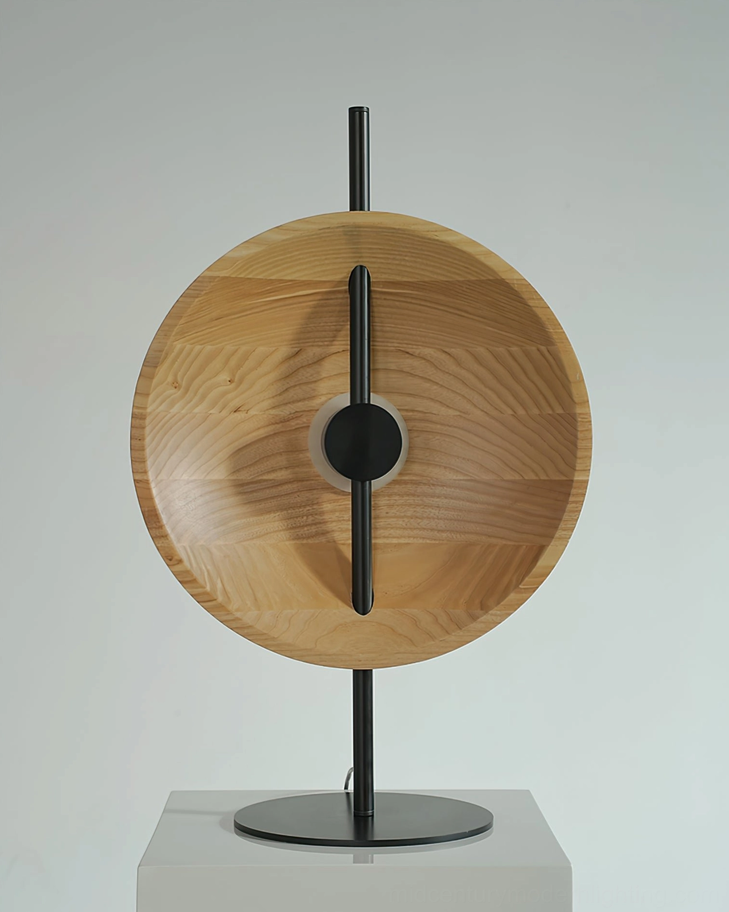 Natural wood Eine table lamp displayed on white pedestal, showcasing solid wood shade and black metal base minimalist design