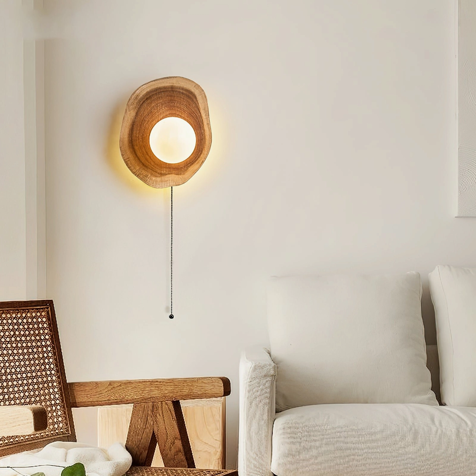 Eivor wall sconce mounted in modern living room setting with sofa and rattan seating, showcasing minimalist warm neutral interior design aesthetic