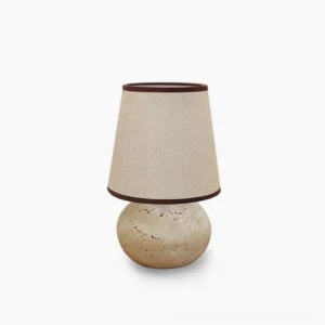 Elba travertine table lamp with linen shade in minimalist white studio setting, front view showing spherical natural stone base