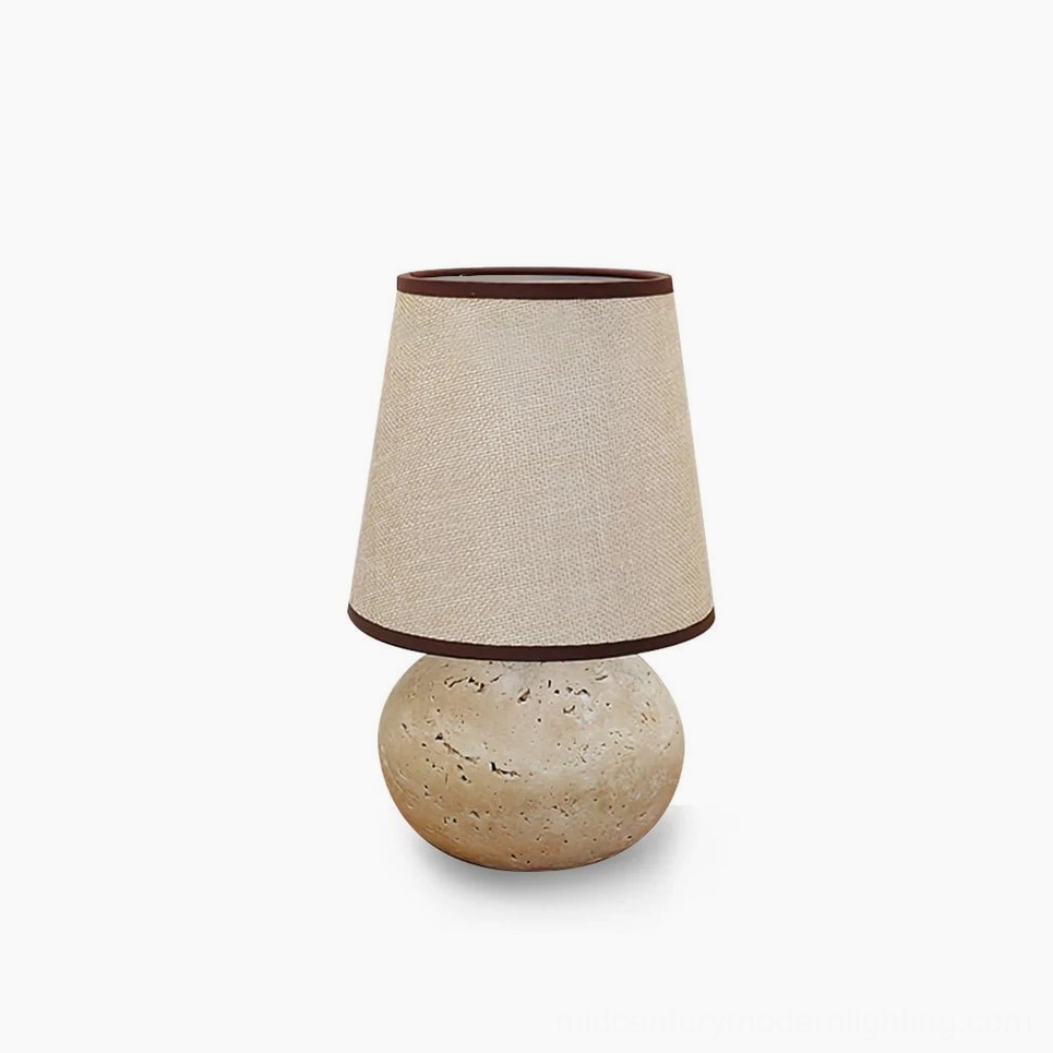 Elba travertine table lamp with linen shade in minimalist white studio setting, front view showing spherical natural stone base