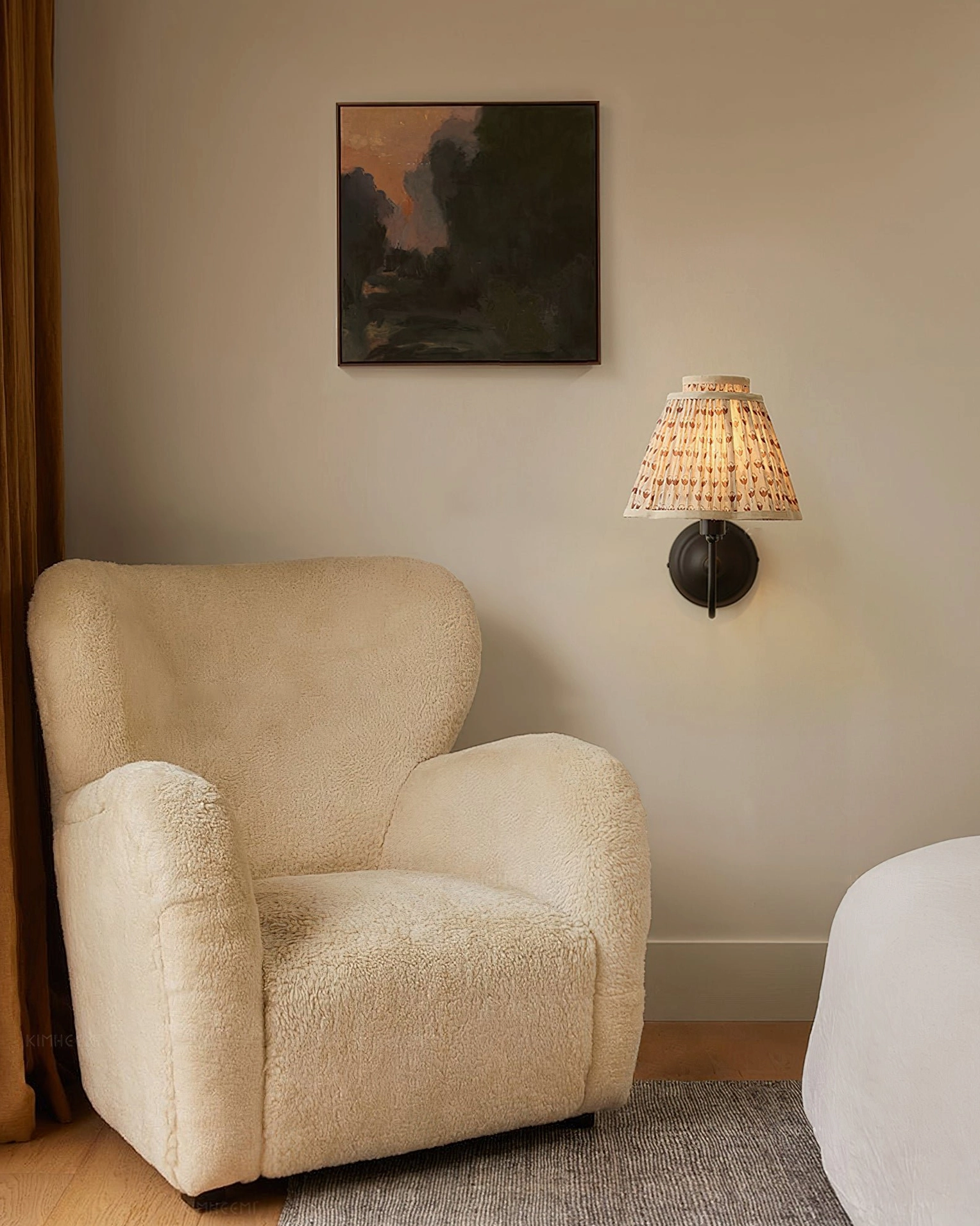 Brown pleated fabric wall sconce in cozy living room setting with lounge chair, warm ambient lighting