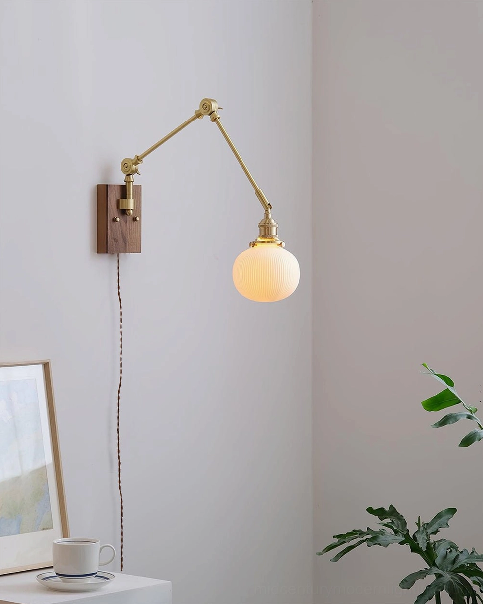 Elia mid-century modern swing arm wall lamp side view next to bedside table with frosted glass globe