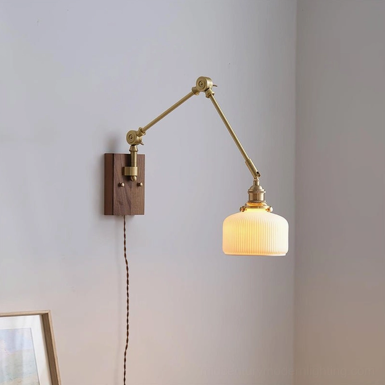 Elia swing arm wall lamp three-quarter side view with flat cylindrical ribbed glass shade and brass framework