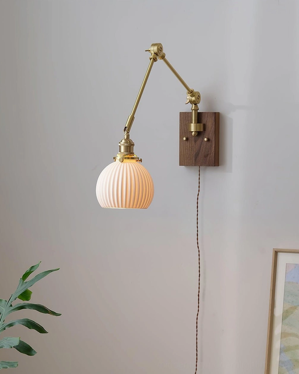Elia swing arm wall lamp three-quarter perspective with ribbed glass shade, brass articulated arm, and walnut base