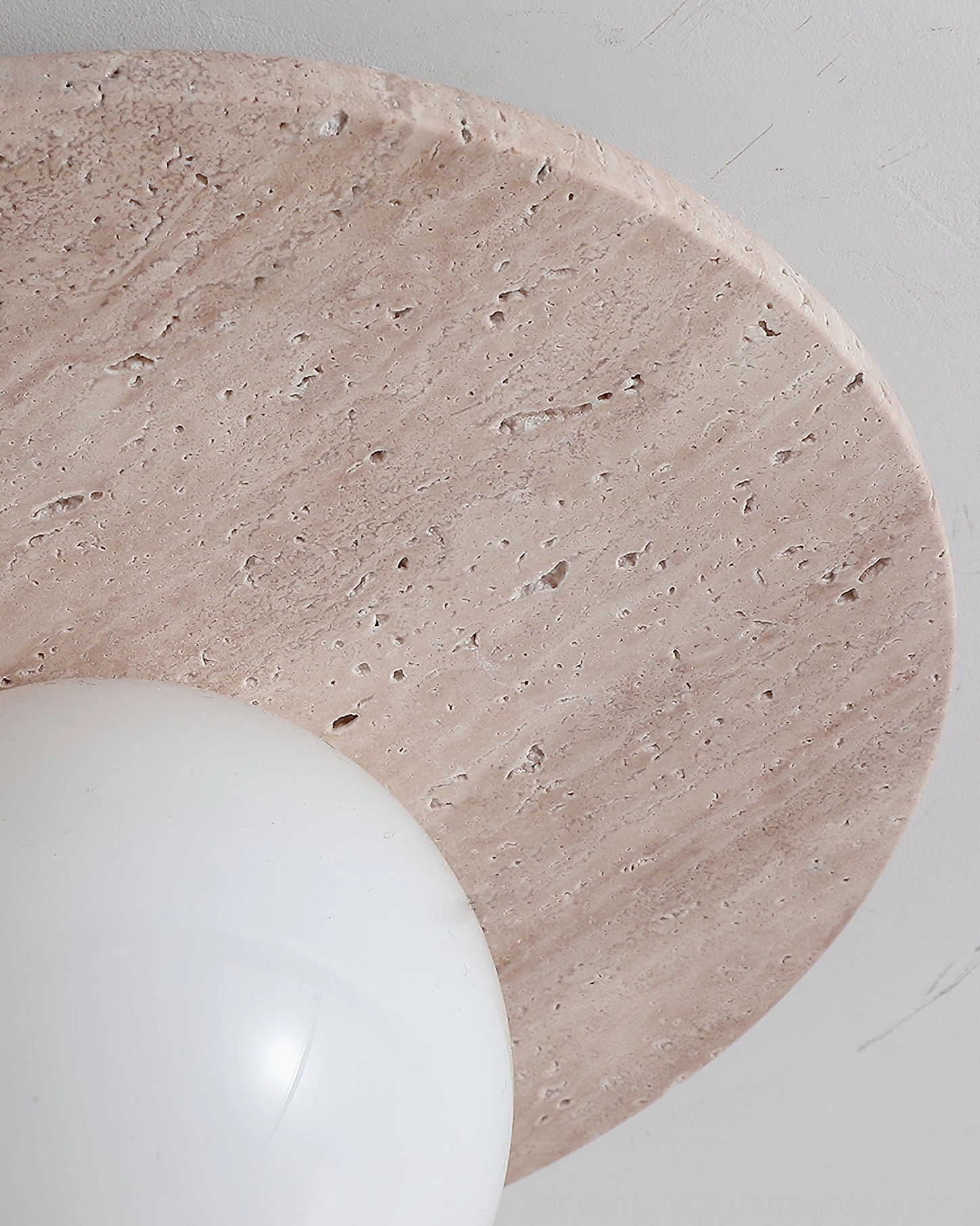 Natural travertine stone wall lamp with glass sphere, close-up detail of stone texture and veining patterns