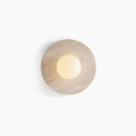 Elira travertine wall lamp with round stone base and glass sphere, front view on white background showing natural stone texture