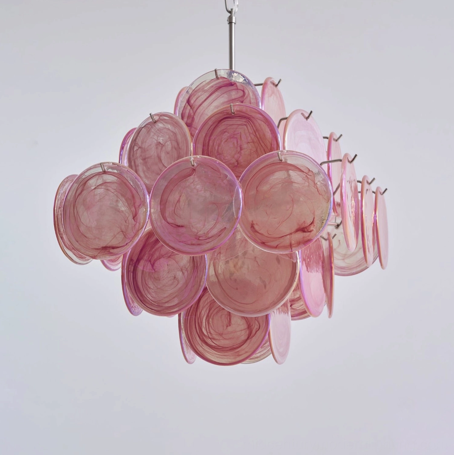 Pink Murano disc chandelier close-up showing clustered round glass discs with polished metal suspension rod and connection hardware
