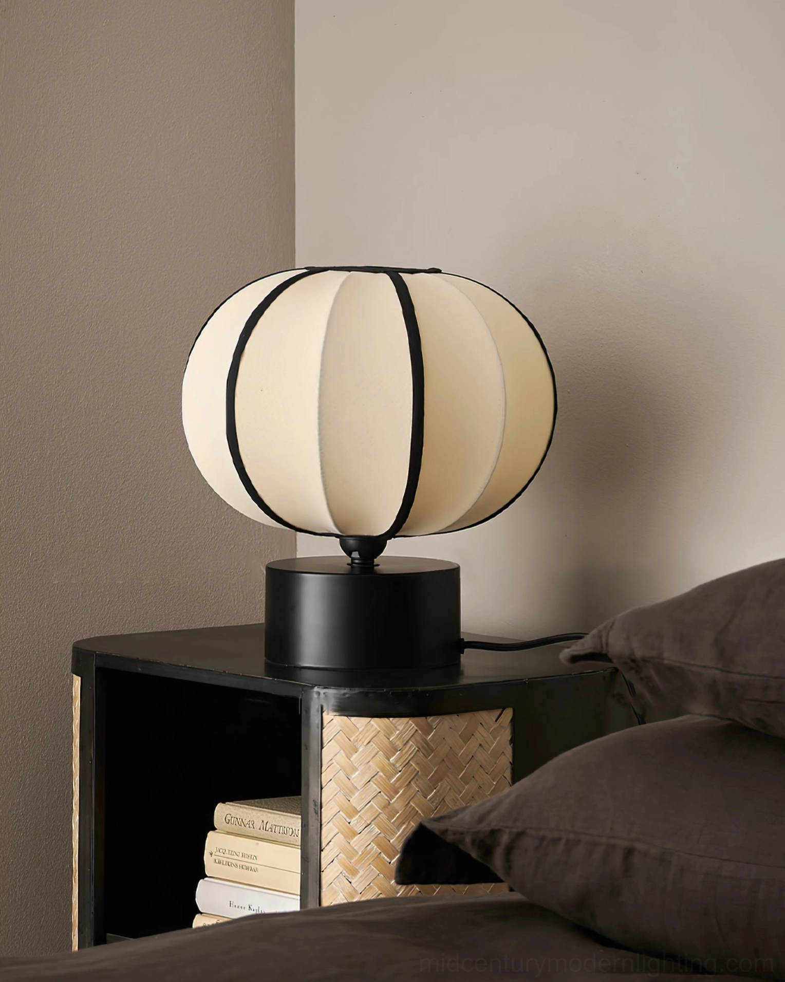 Ellos lantern table lamp on bedside with stacked books in minimal bedroom interior