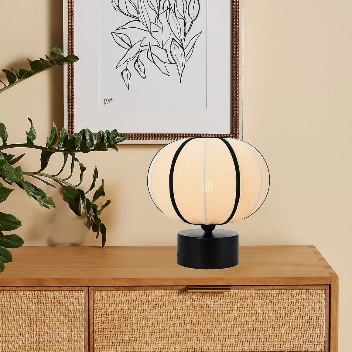Ellos lantern lamp placed on rattan-front wooden dresser with botanical wall art
