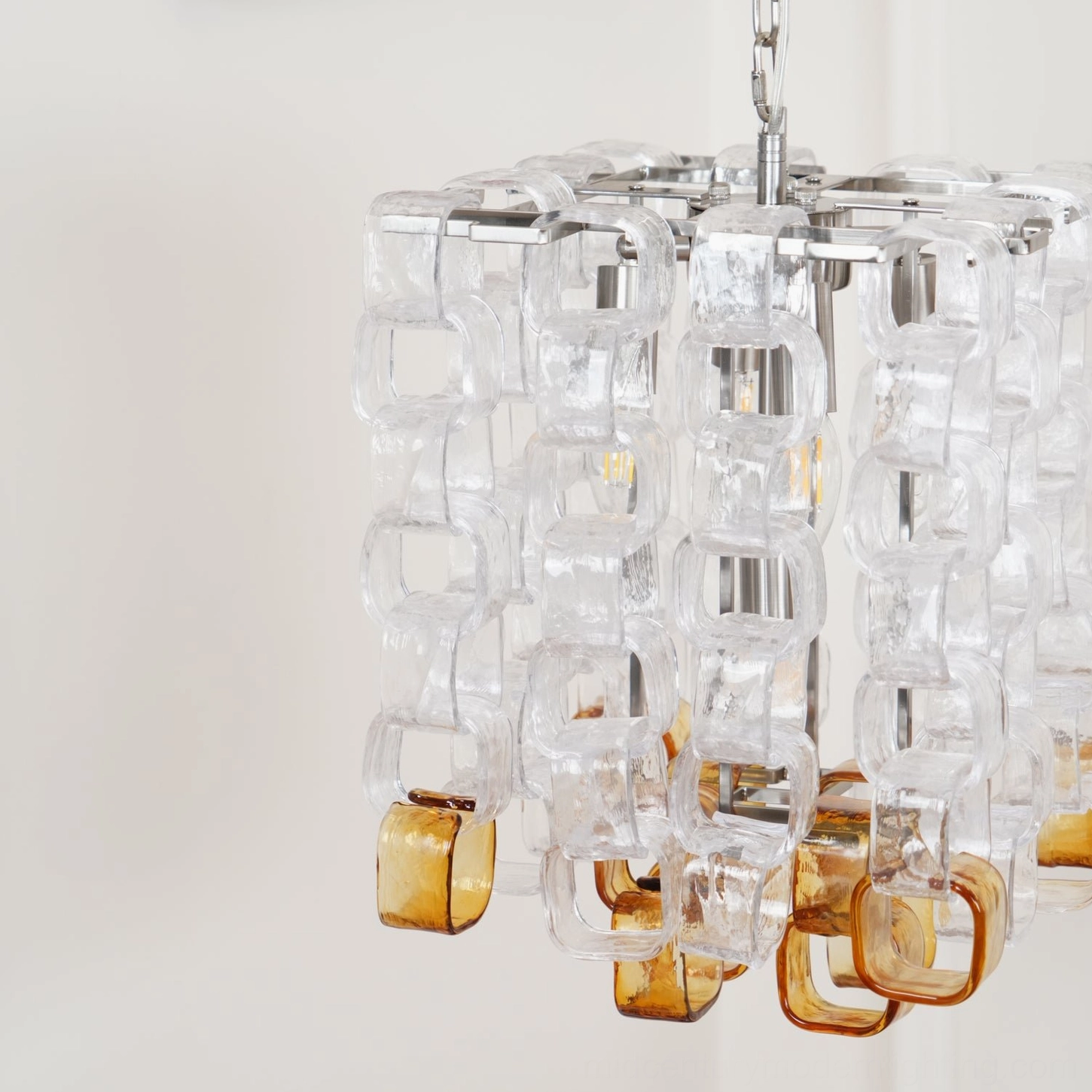 Close-up detail of stacked clear and amber glass blocks on Elodie Murano chandelier, chrome hardware at top, studio lighting