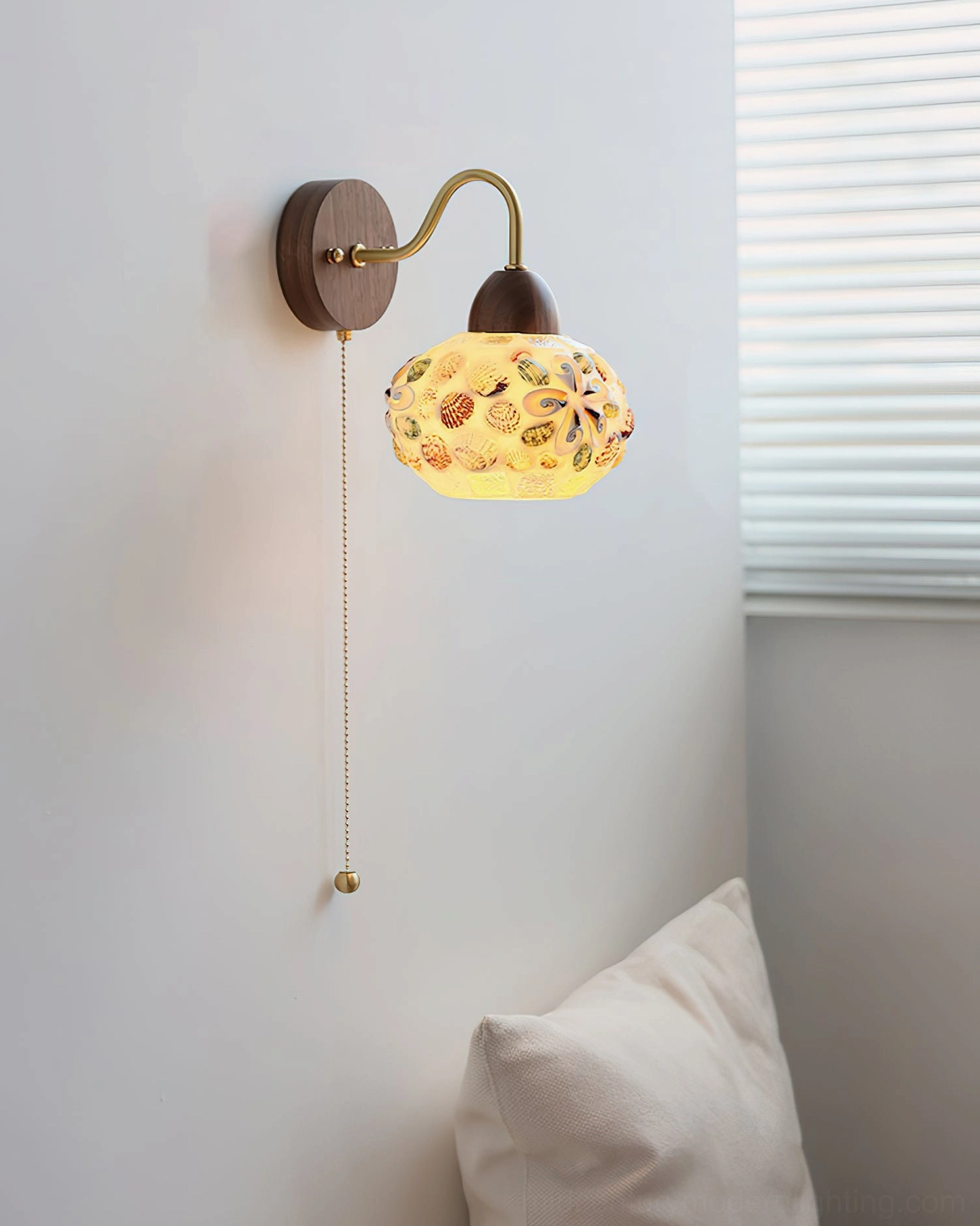 Embossed glass wall lamp with floral pattern and warm yellow glowing light in bedroom setting - front oblique angle