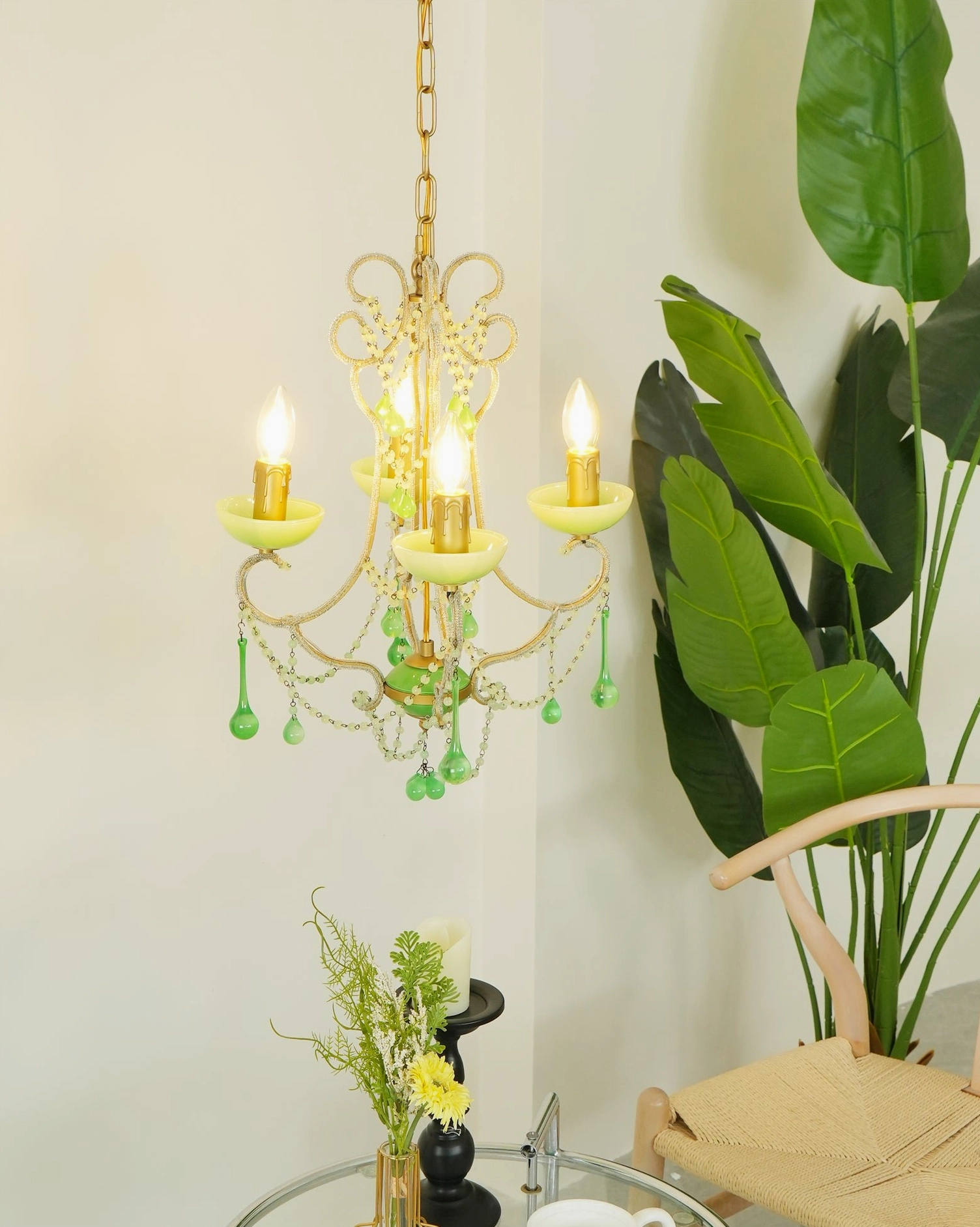Three-light emerald green Murano chandelier in cozy cafe studio setting with glass table and floral decor