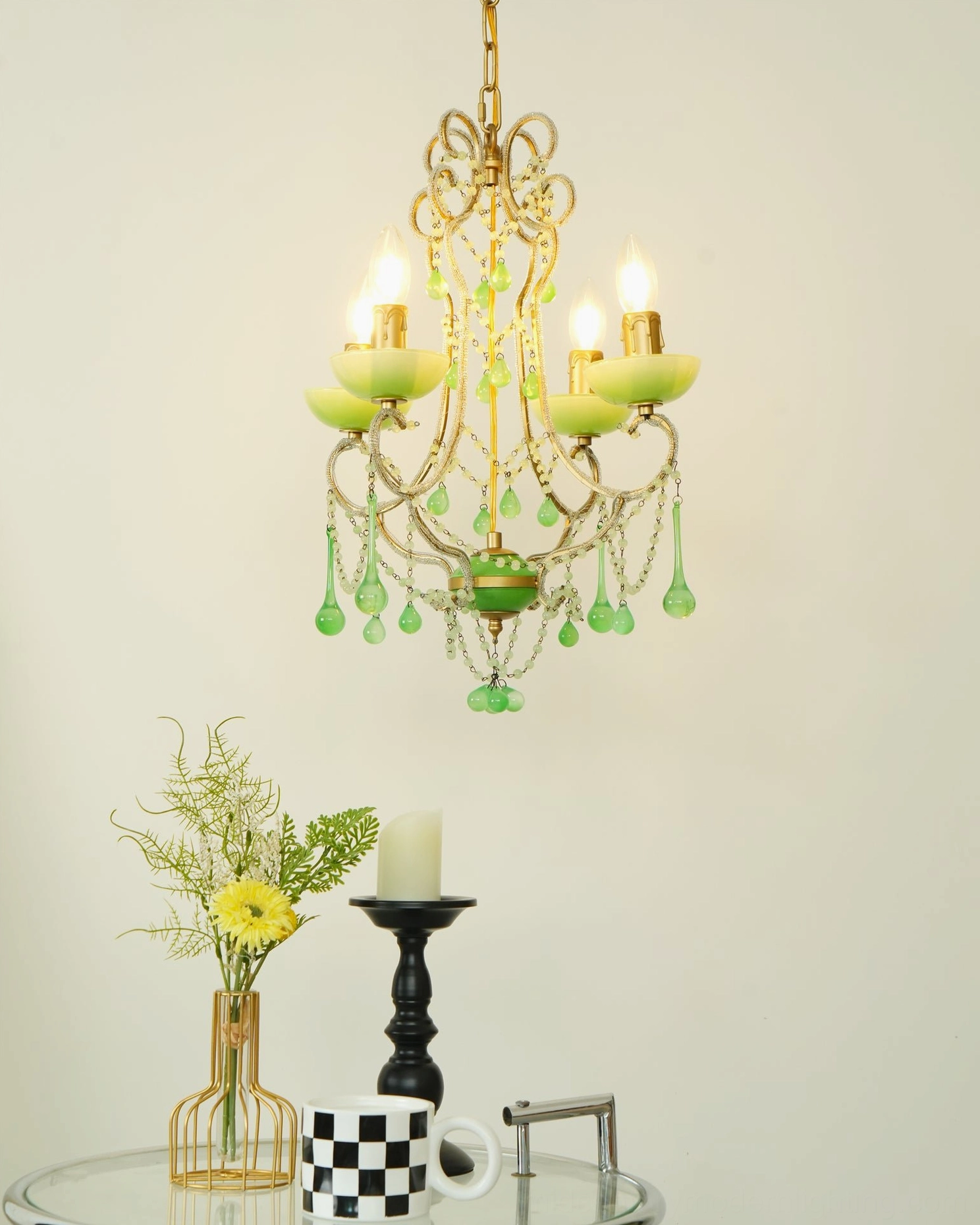Four-light emerald green chandelier featuring crystal pendants and gold metal accents in studio setting