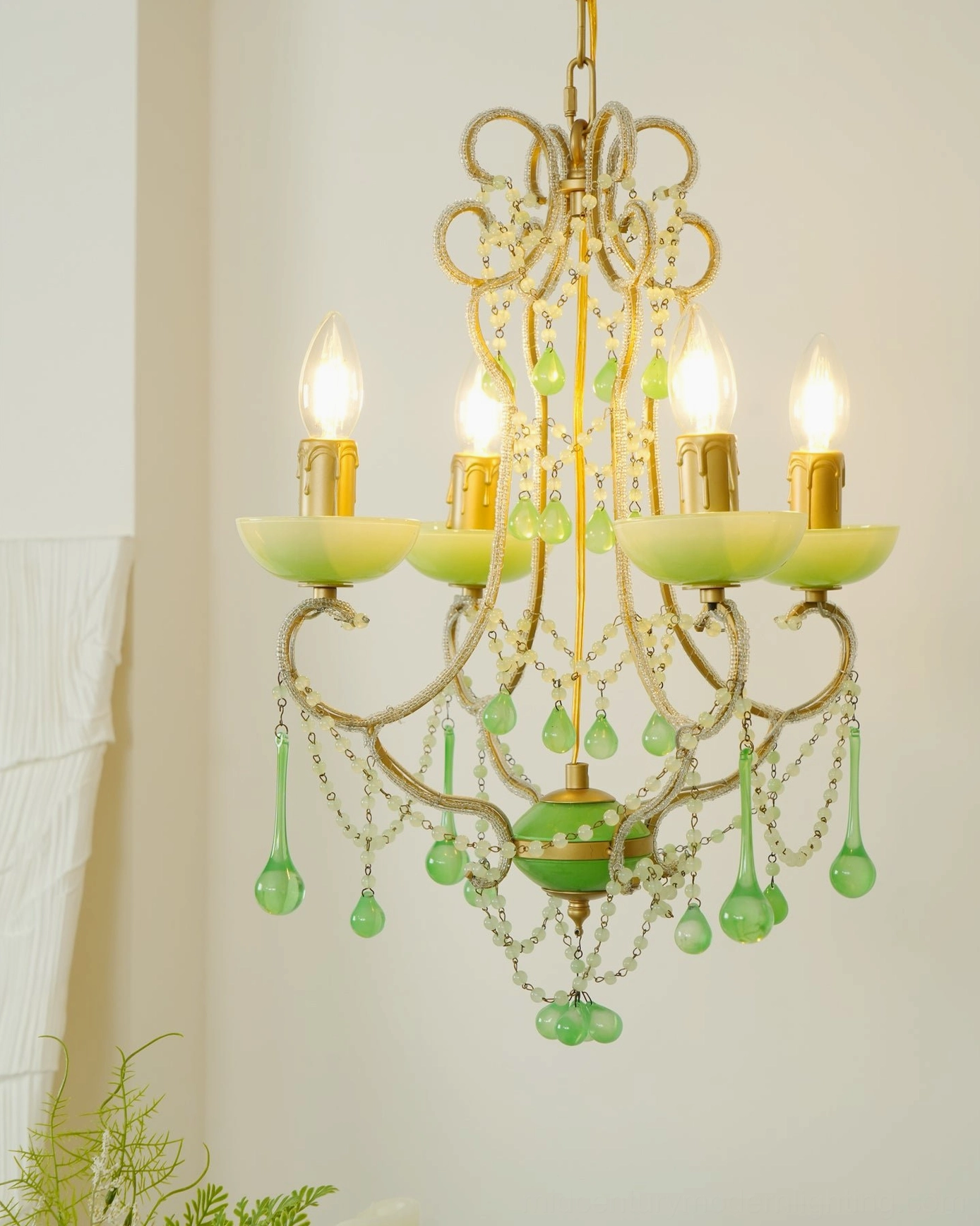 Illuminated emerald green chandelier with glowing candle-style bulbs and ornate metal framework, low-angle view