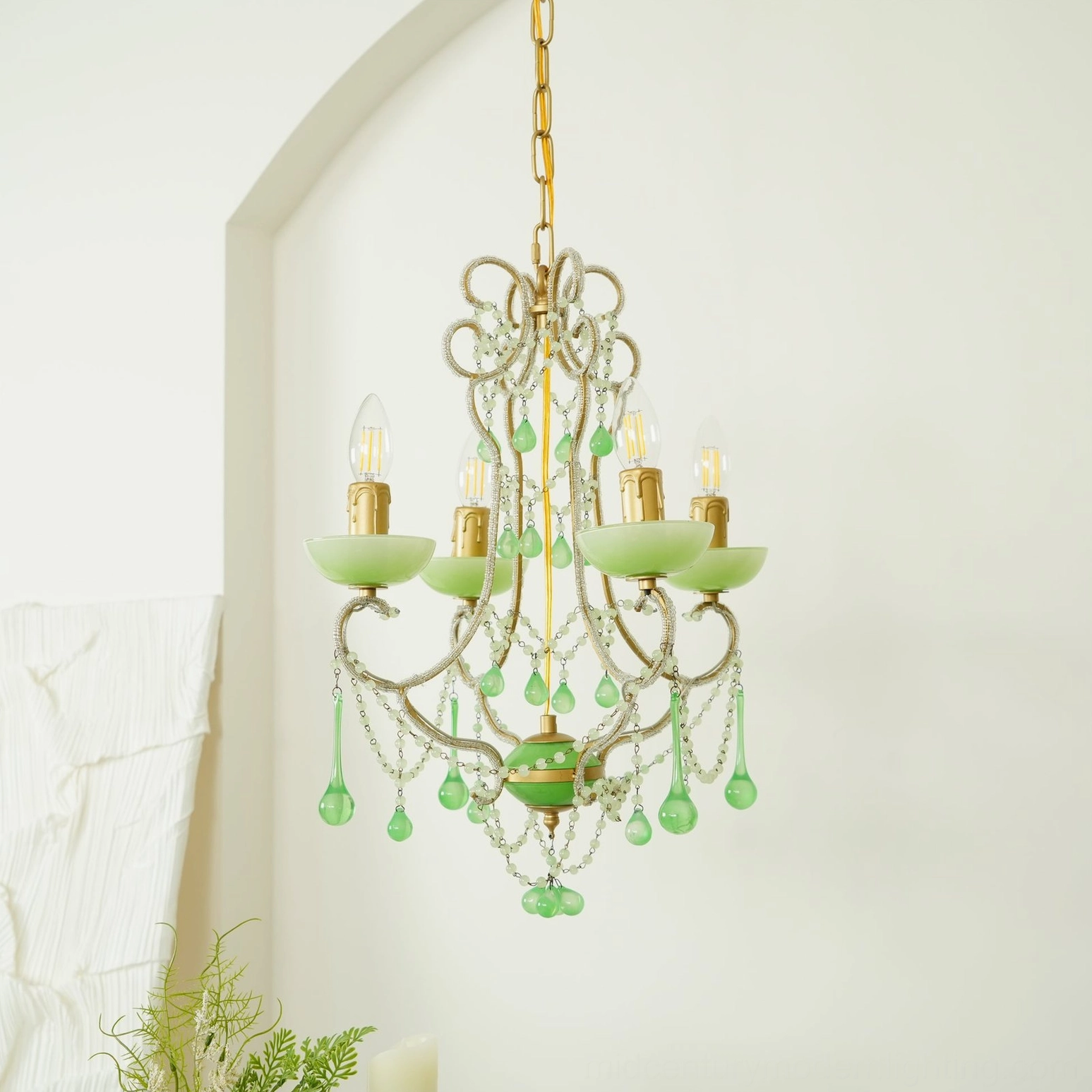 Vintage emerald glass chandelier with gold suspension chain displayed in minimalist studio setting with arched wall