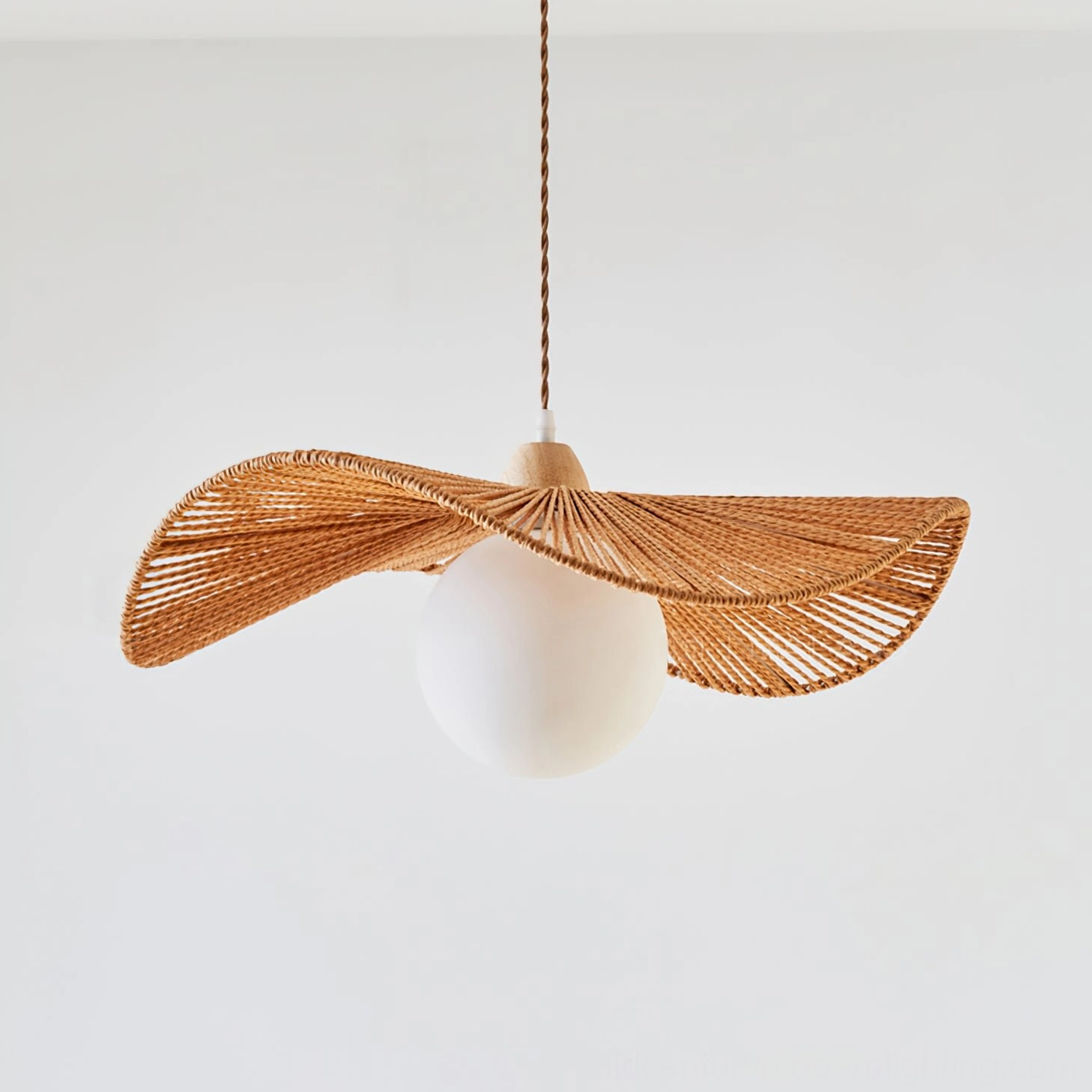 Unlit Emmi rope pendant lamp with natural hemp shade and twisted hanging cord on white studio background