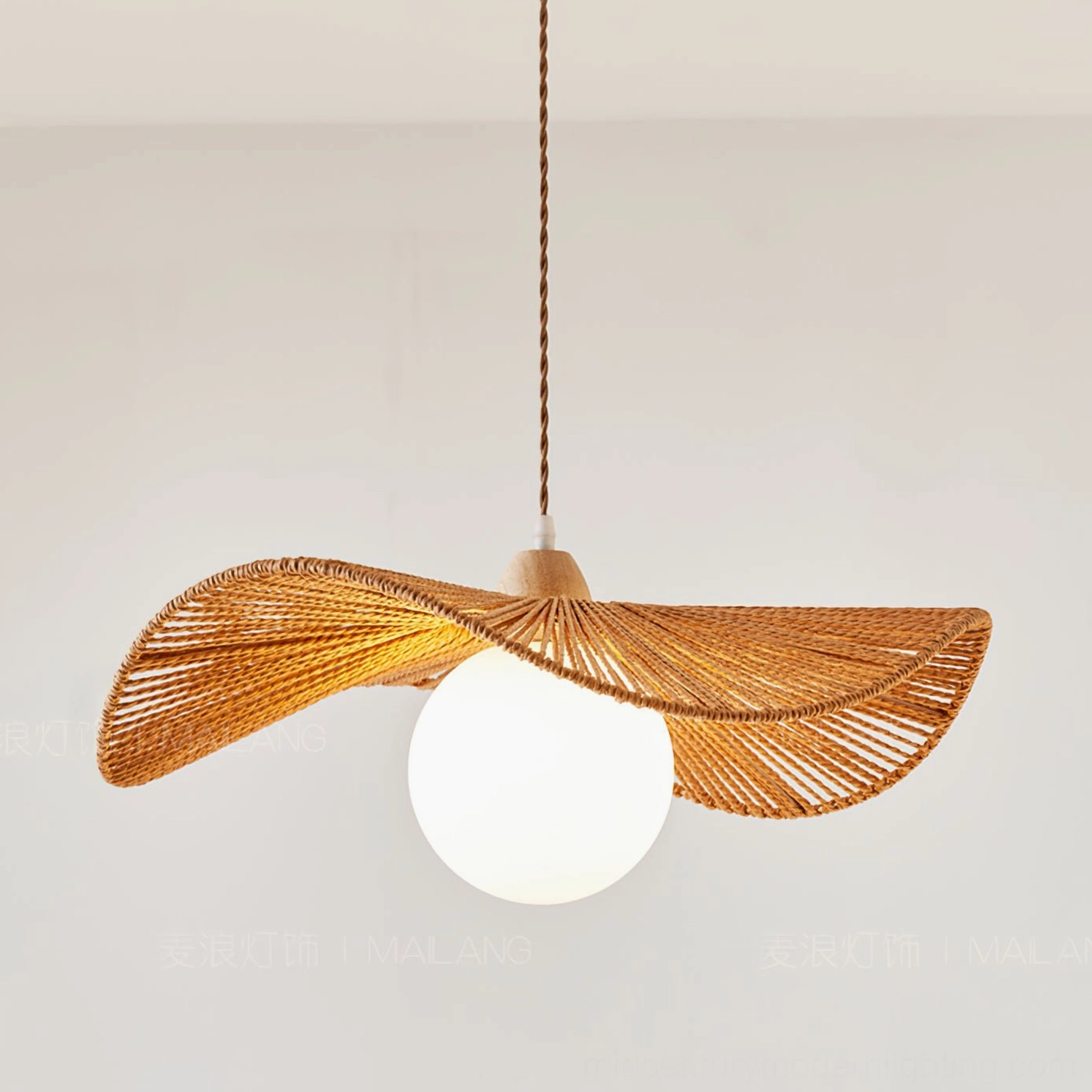 Illuminated Emmi rope pendant lamp with glowing Edison bulb and twisted fabric cord hung against indoor wall