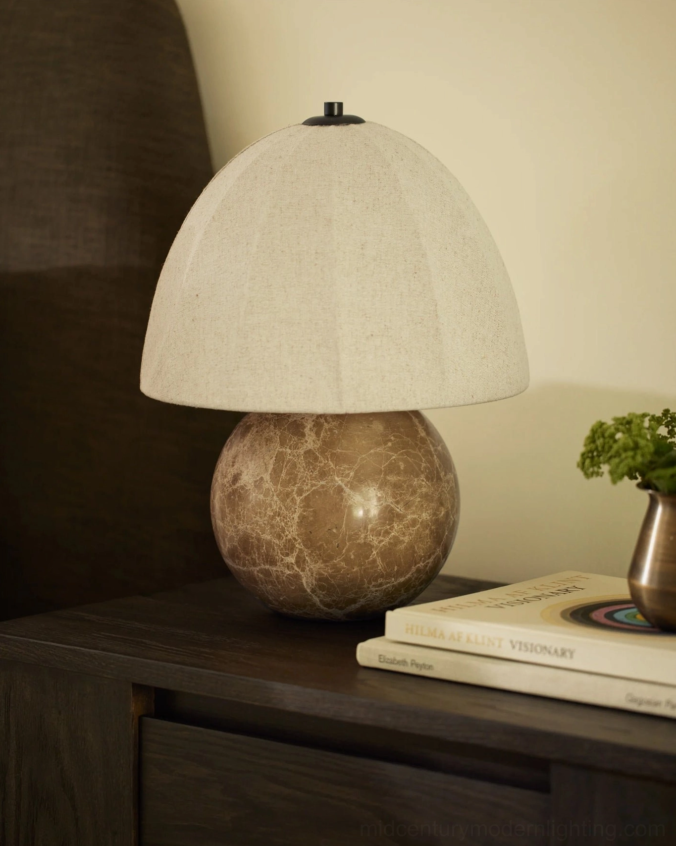 Enora marble table lamp close-up three-quarter view next to potted succulent plant, warm ambient lighting