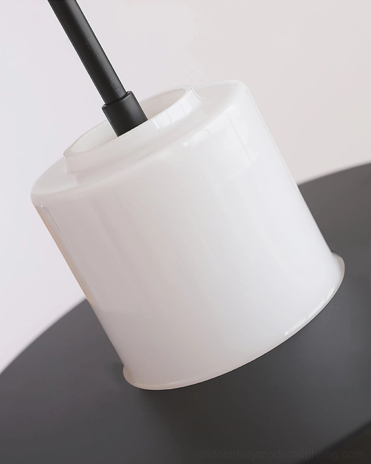 Close-up of pendant lamp fixture hardware showing smooth white surface and black metal hanging rod