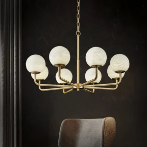 Erich chandelier illuminated in luxury dark interior with polished brass frame and glowing alabaster globes