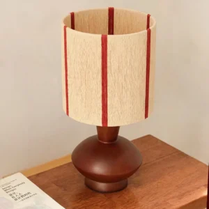 Ernest table lamp three-quarter angle showing walnut wood base and vertical striped textile shade on wooden furniture