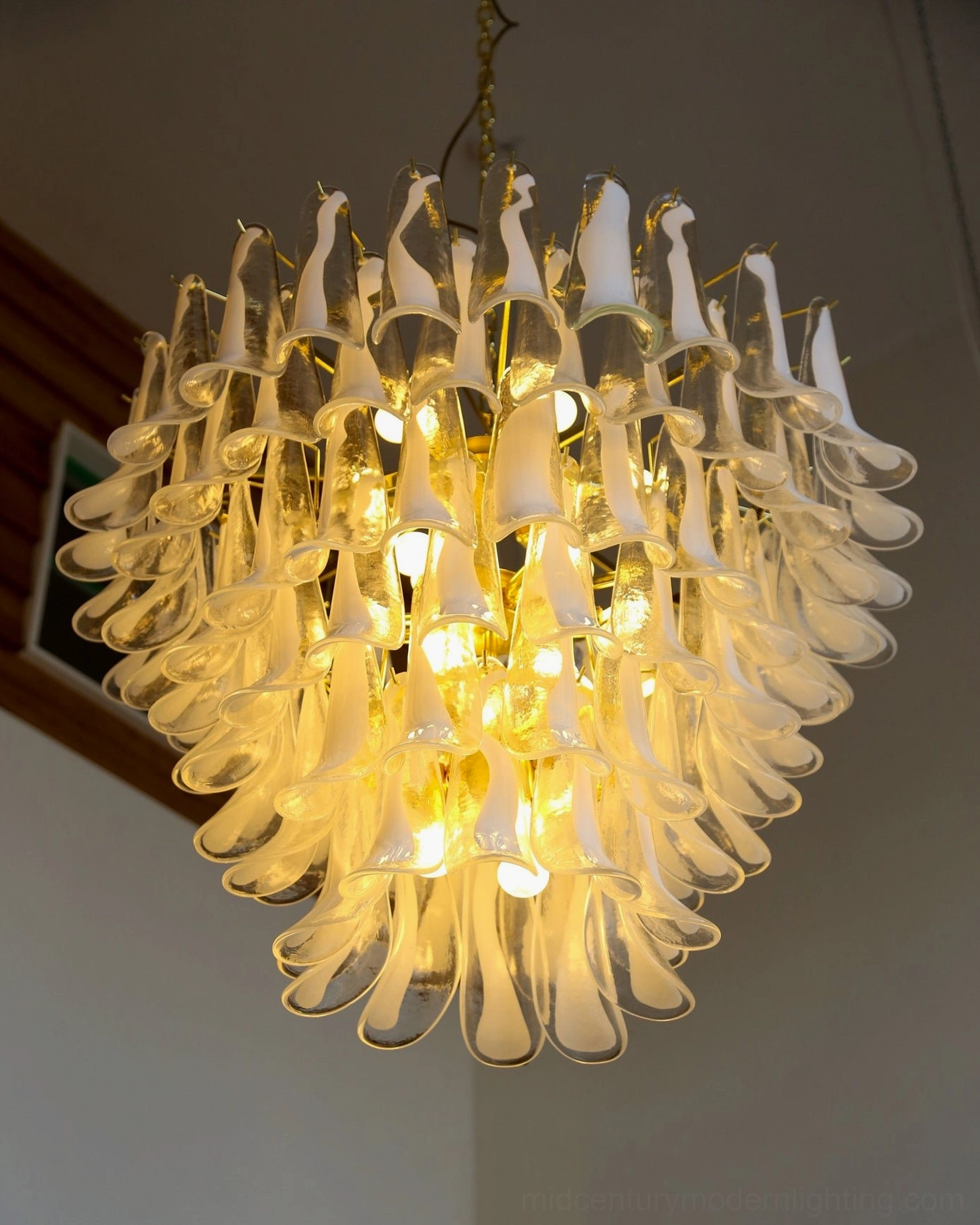 Full view of illuminated ethereal petal chandelier in residential home space showing cascading glass petals and complete light distribution