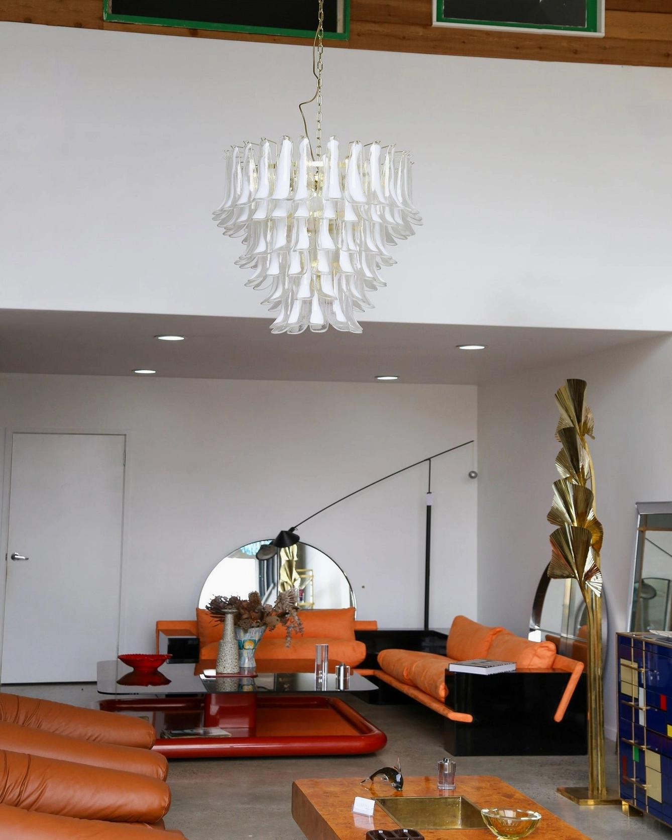 Distant view of white glass petal chandelier hanging in luxury modern living room demonstrating scale and presence in spacious interior