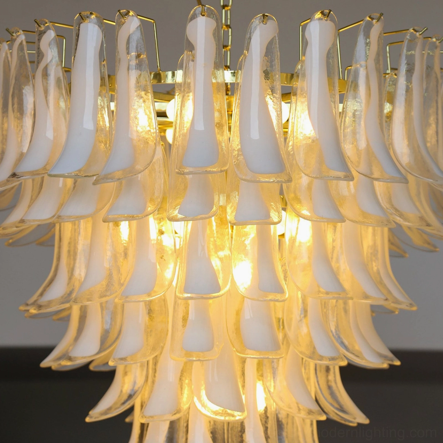 Side angle close-up of illuminated glass petals displaying warm golden light reflection and tiered layering of Murano-style glass