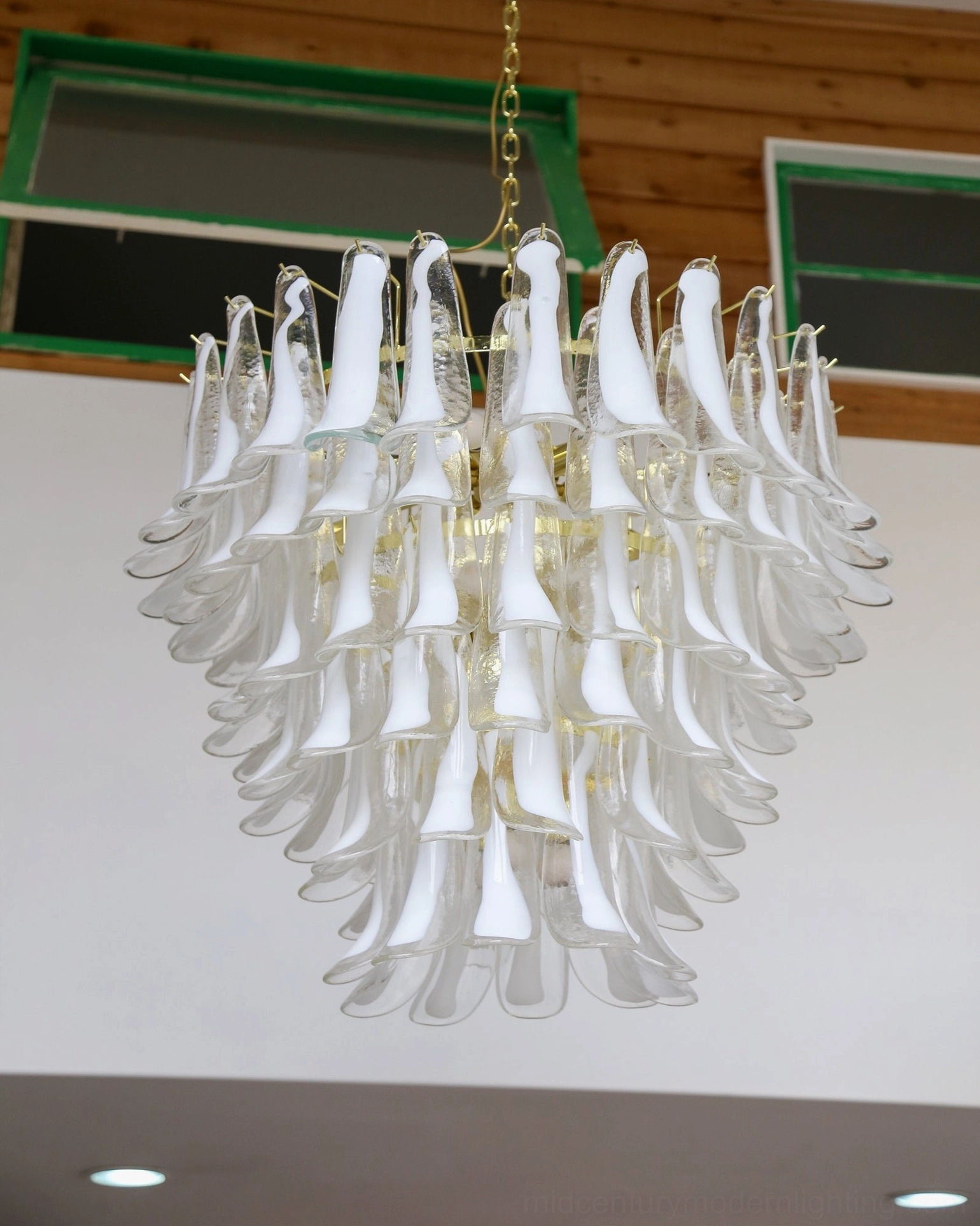 All-white frosted glass petal chandelier installed in contemporary minimalist modern living room demonstrating mid-century lighting aesthetic