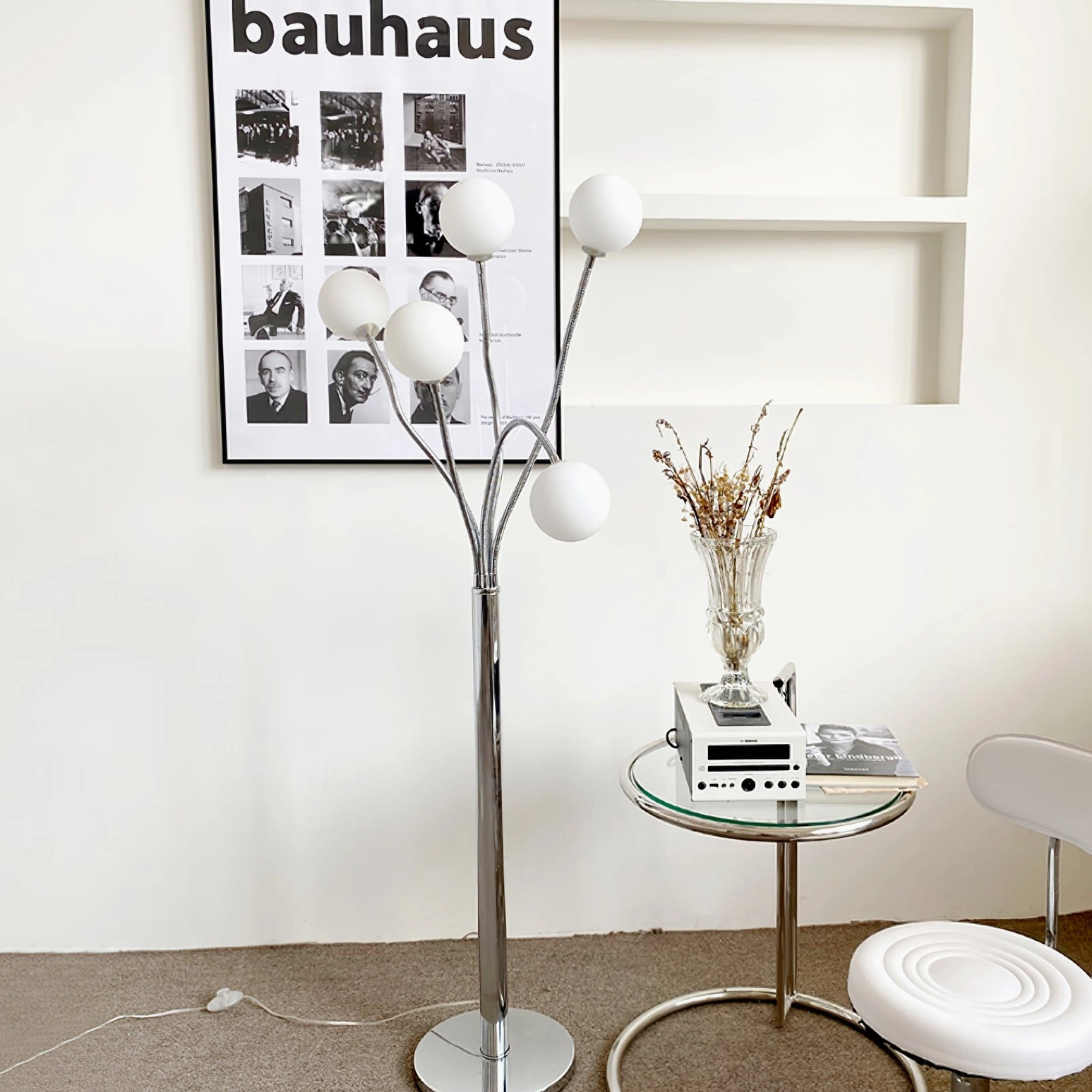 Multi-head floor lamp with white globe shades and silver metal pole paired with glass side table and Bauhaus wall art