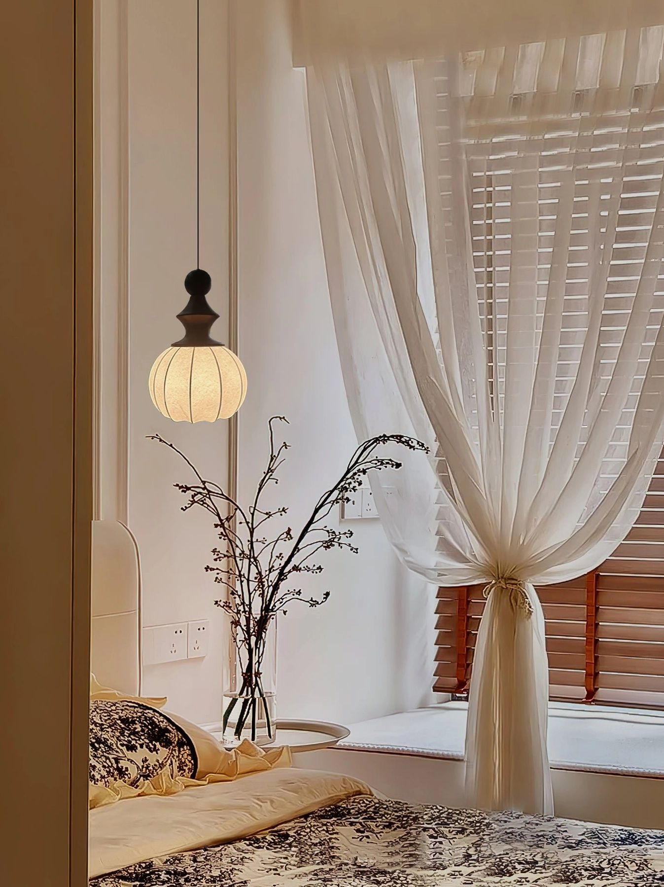 Fabric pendant light creating warm minimalist vintage ambiance in bedroom with sheer window curtains and natural daylight